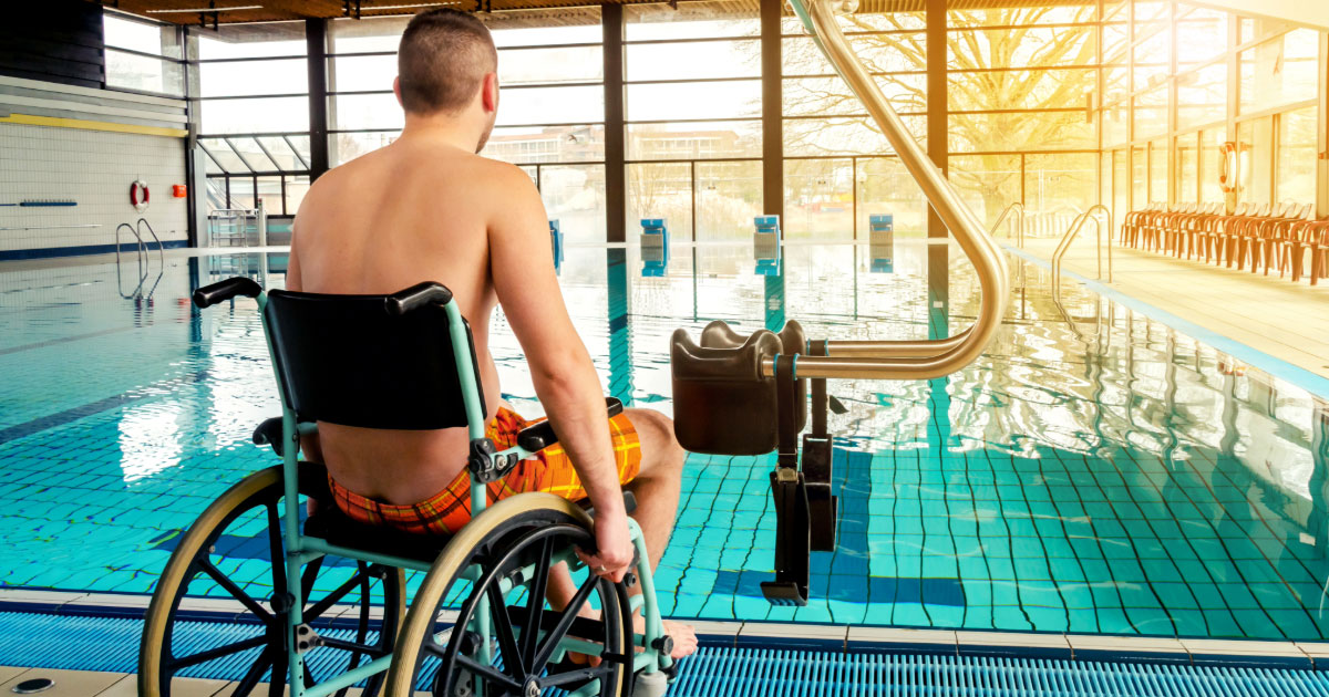 Man in a wheelchair getting ready to use swimming pool accessibility lift