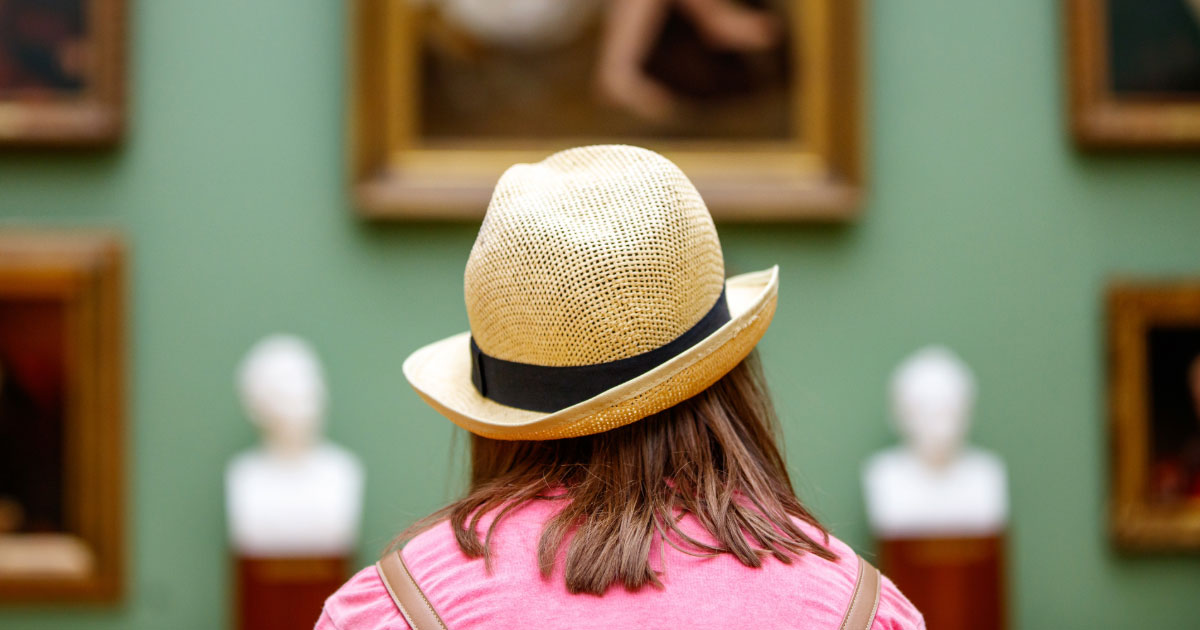 Woman sitting down in art gallery appreciating the paintings on the wall