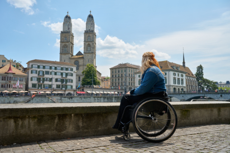 woman in wheelchair in front of city buildings