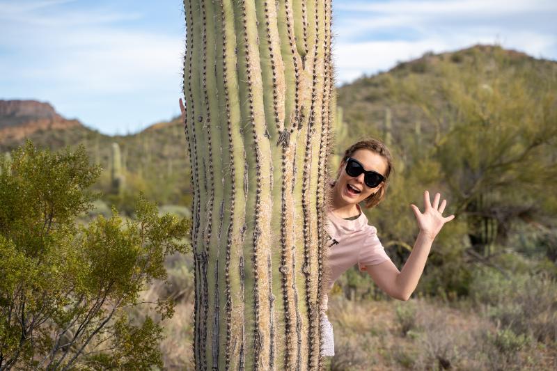 woman peeking out behind a saguaro in the Sonoran Desert near Scottsdale