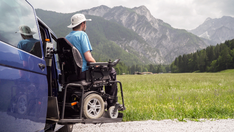 man in wheelchair coming out of accessible van with view of mountains
