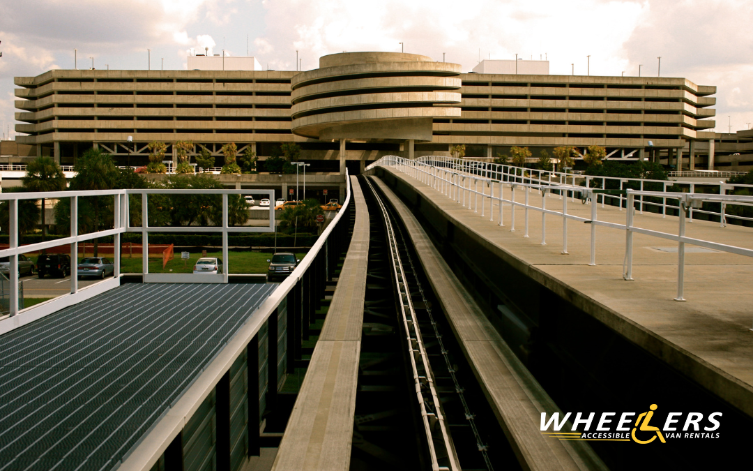 Exterior of Tampa International Airport featuring its elevated people mover track and circular terminal building under a partly cloudy sky.